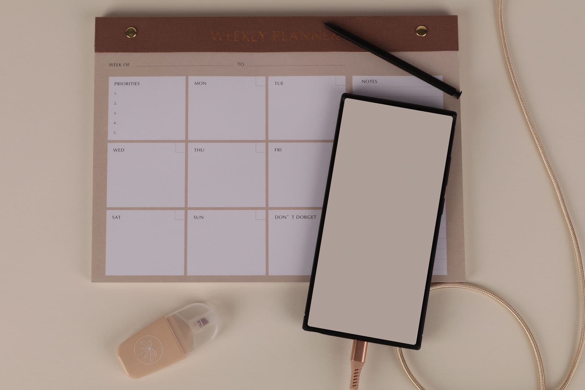A weekly planner, pen, and phone laid out on a desk
