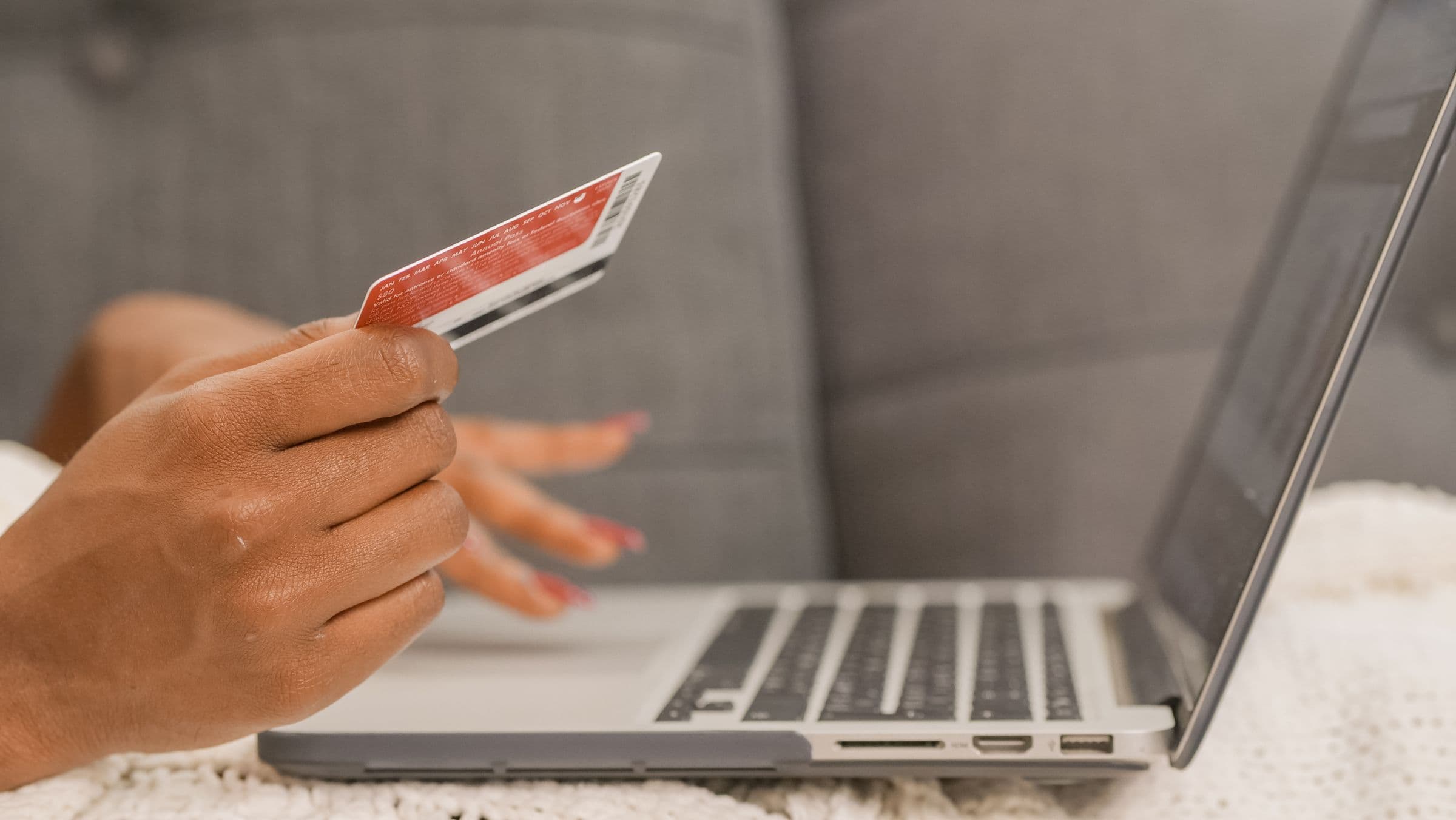 A shopper checking out on a laptop with a credit card in hand