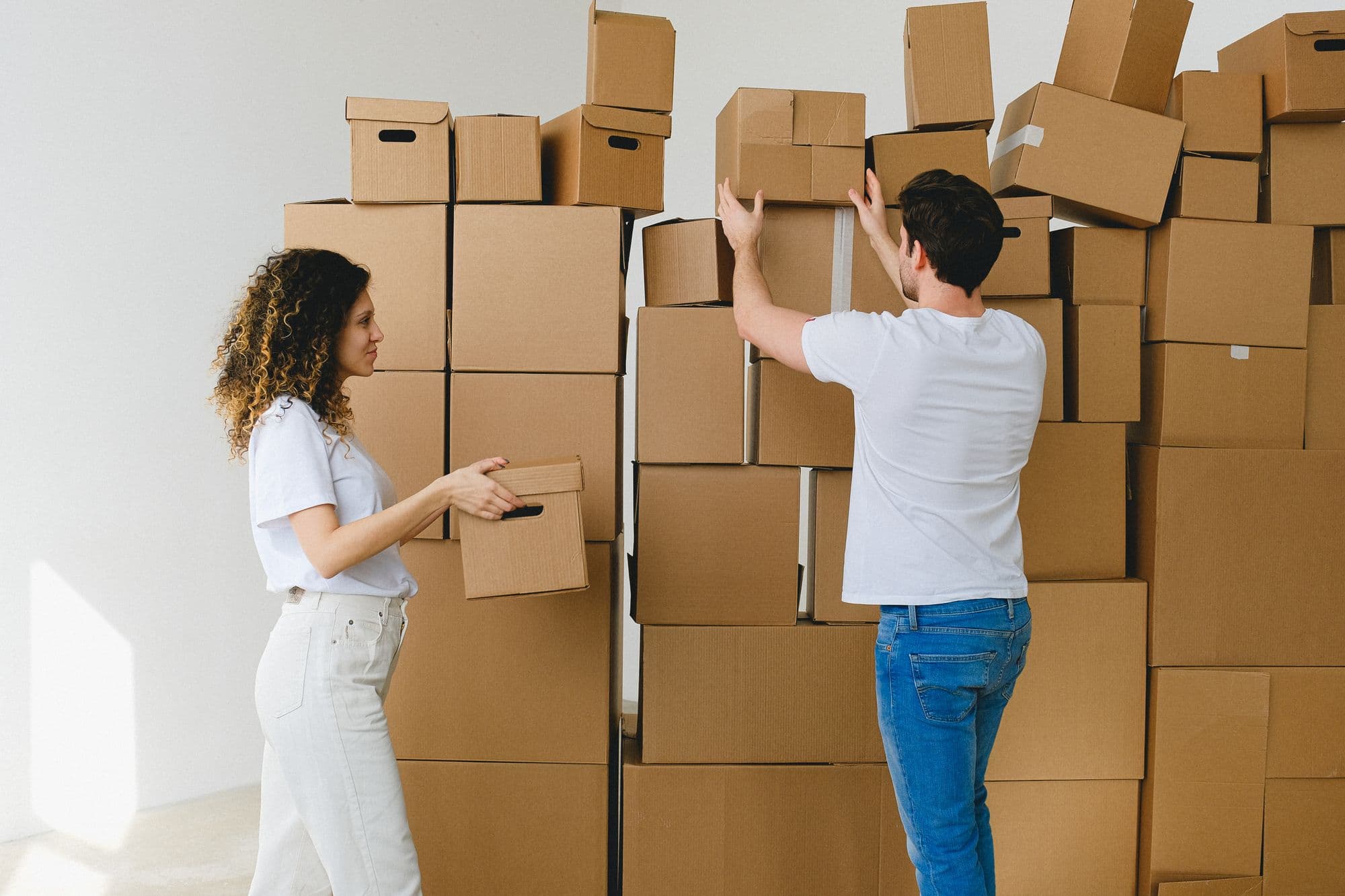 Two people stacking cardboard moving boxes